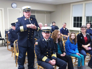 Plympton Fire Chief Warren Borsari stands and addresses the Board of Selectmen while a full crowd sits behind him and Steven Winslow, about to be appointed Deputy Fire Chief sits in the front row with his daughters and wife. Photo by Abrahm Neal.