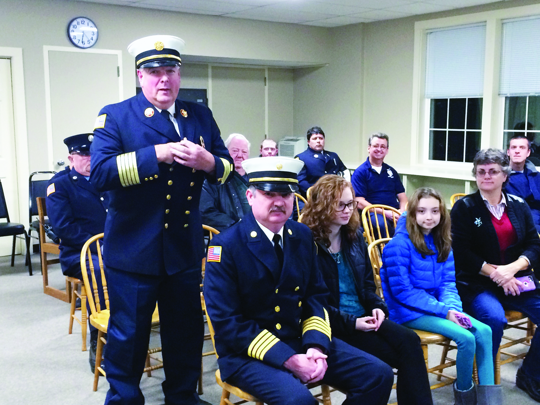 Plympton Fire Chief Warren Borsari stands and addresses the Board of Selectmen while a full crowd sits behind him and Steven Winslow, about to be appointed Deputy Fire Chief sits in the front row with his daughters and wife.